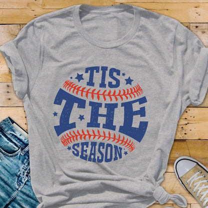 May include: Gray t-shirt with a baseball graphic and the text "Tis the Season" in blue and red.