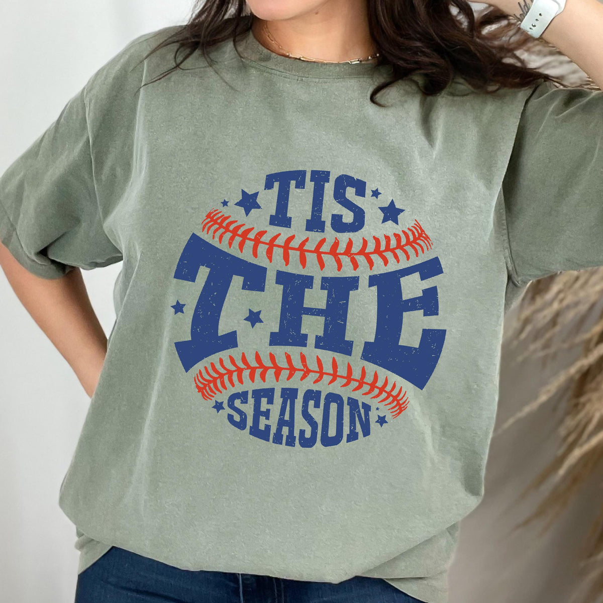 May include: A green t-shirt with a baseball graphic and the text "Tis the Season" in blue and red.