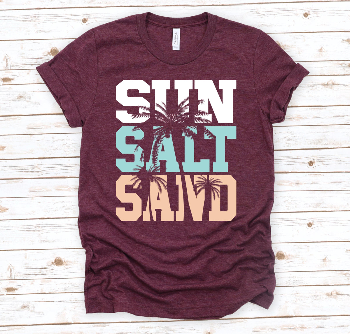 May include: Burgundy t-shirt with the words "Sun Salt Sand" in white, blue, and peach with palm trees between the words.