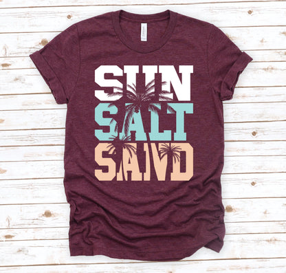 May include: Burgundy t-shirt with the words "Sun Salt Sand" in white, blue, and peach with palm trees between the words.