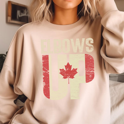 May include: A light beige sweatshirt with a distressed graphic of a Canadian flag and the text "Elbows Up".
