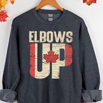 May include: A dark gray sweatshirt with the text "Elbows Up" in white letters. The text is overlaid with a distressed Canadian flag design in red and white.