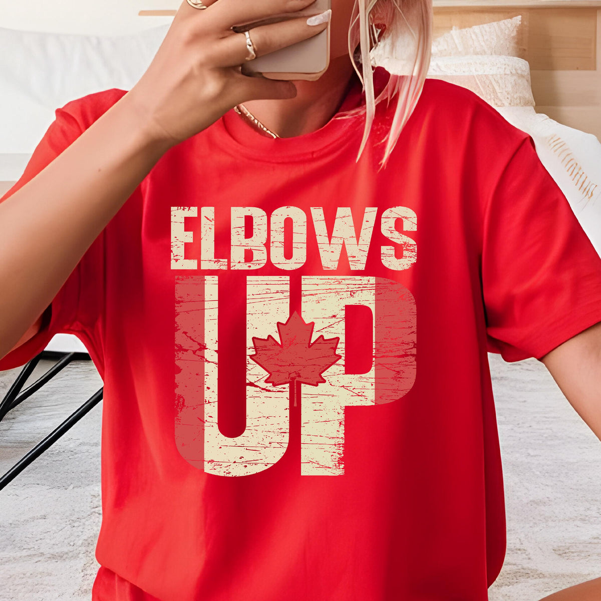 May include: Red t-shirt with a distressed white graphic that says "Elbows Up" with a Canadian flag maple leaf in the middle of the "U".