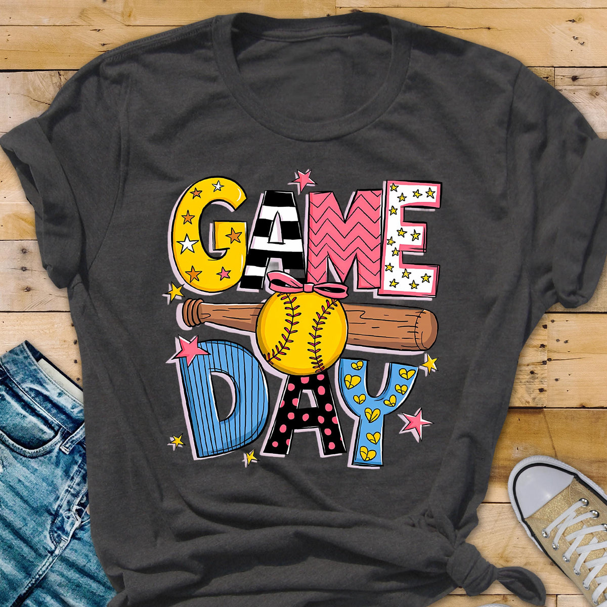 May include: A dark gray t-shirt with the words "GAME DAY" in colorful, patterned letters. A softball and bat are behind the letters.