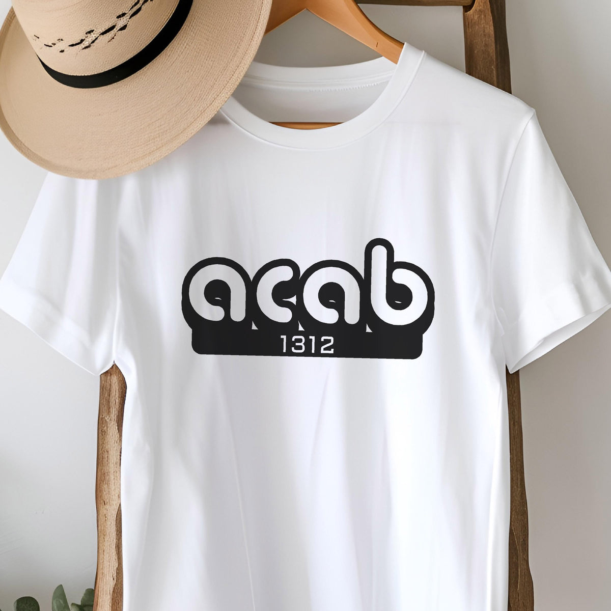 May include: White t-shirt with a black graphic of the acronym "ACAB" in a rounded font with the number "1312" underneath.