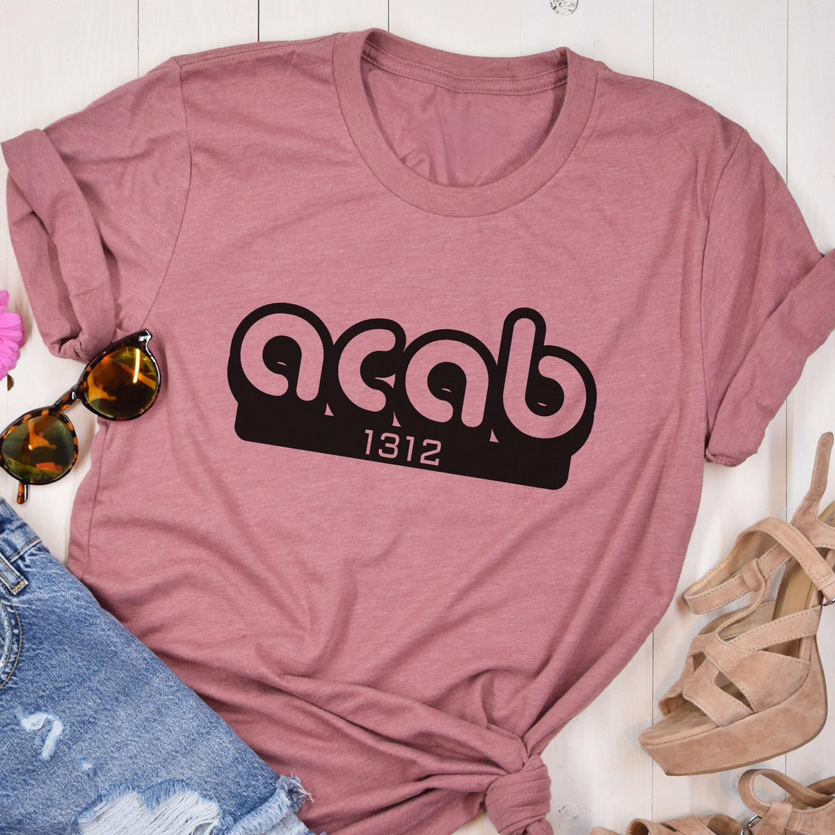 May include: A pink t-shirt with the text "acab 1312" printed in black.