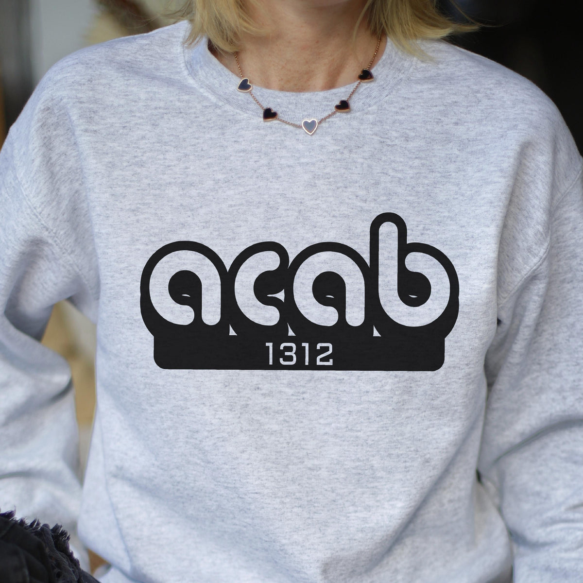 May include: A gray sweatshirt with a black graphic print of the text "ACAB" in a stylized font with the number "1312" underneath.