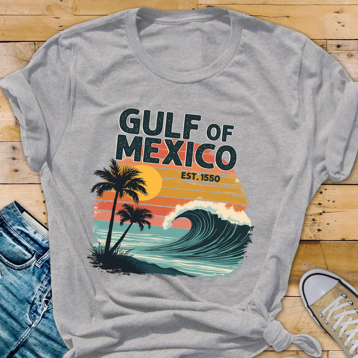 May include: Gray t-shirt with a retro-style graphic design featuring a wave, palm trees, and the text "GULF OF MEXICO EST. 1550".