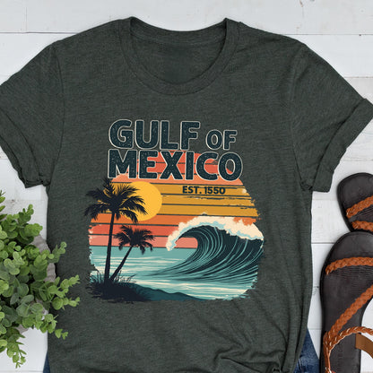 May include: A dark green t-shirt with a retro-style graphic design featuring a palm tree, a sunset, and a wave. The text "GULF OF MEXICO EST. 1550" is printed on the shirt.