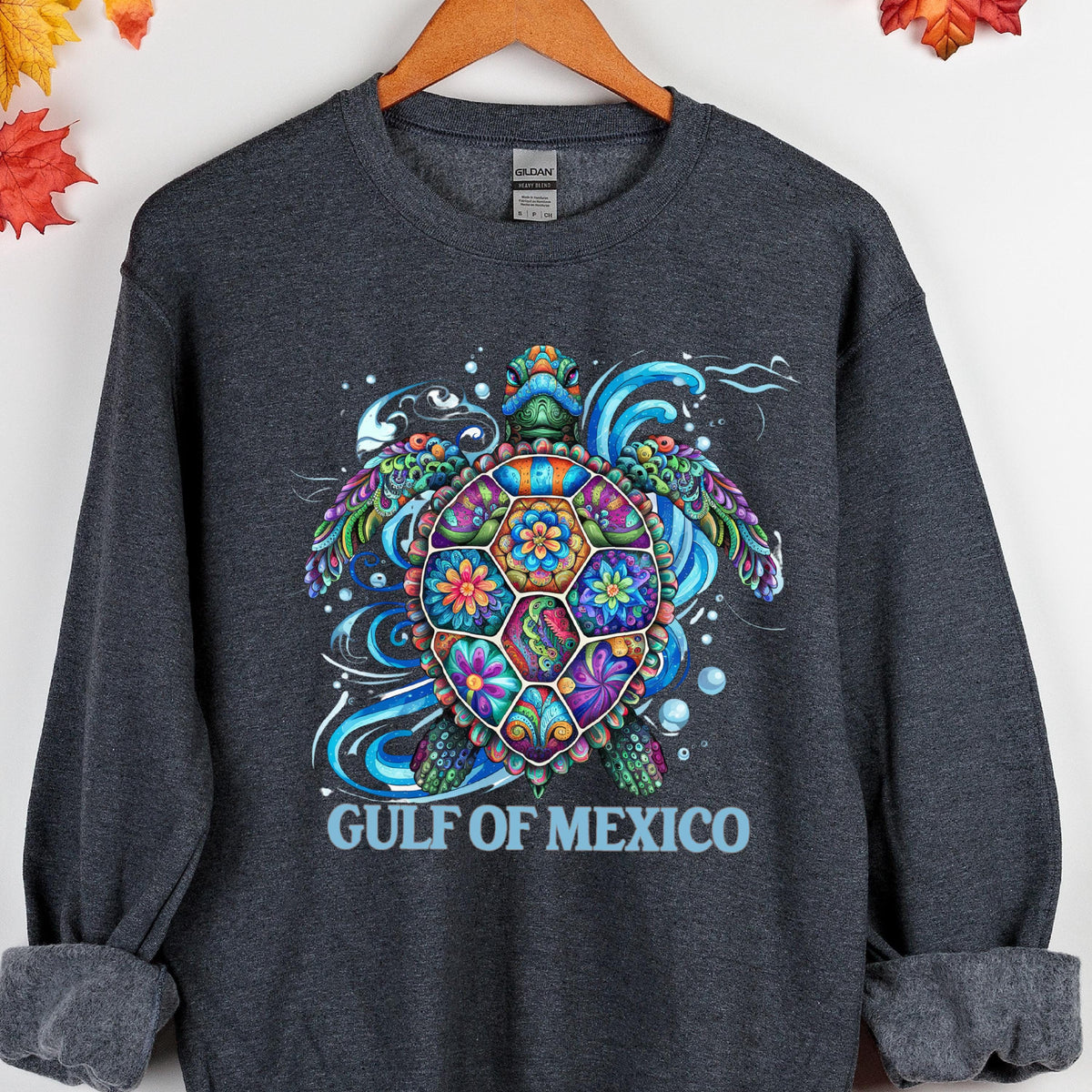 May include: Dark gray sweatshirt featuring a colorful sea turtle design. The turtle has a patterned shell with floral and geometric shapes in shades of blue, green, purple, and orange. The text "GULF OF MEXICO" is printed below the turtle.