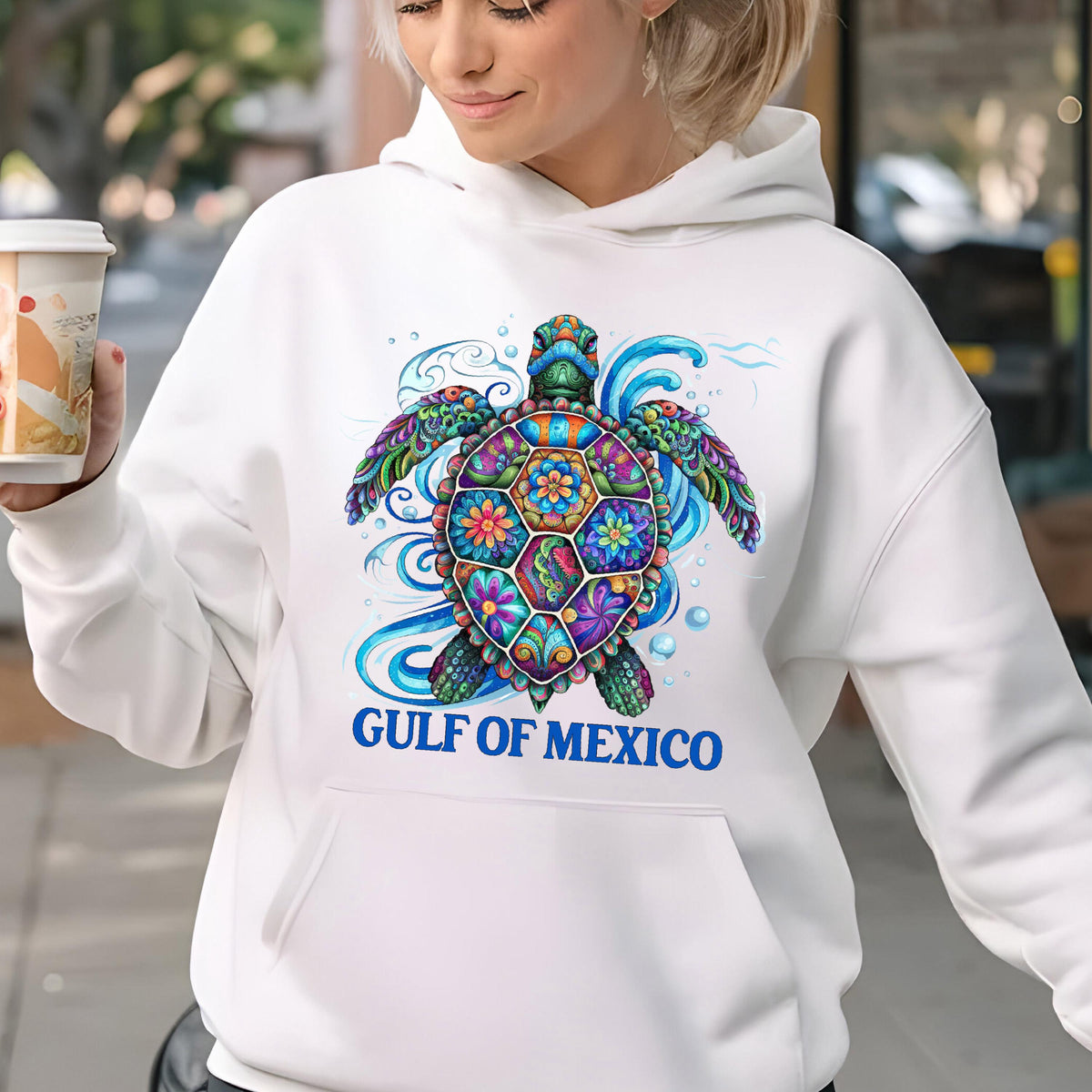 May include: White hooded sweatshirt featuring a colorful sea turtle design. The turtle has a patterned shell with floral and geometric shapes in various colors. The text "GULF OF MEXICO" is printed in blue below the turtle.