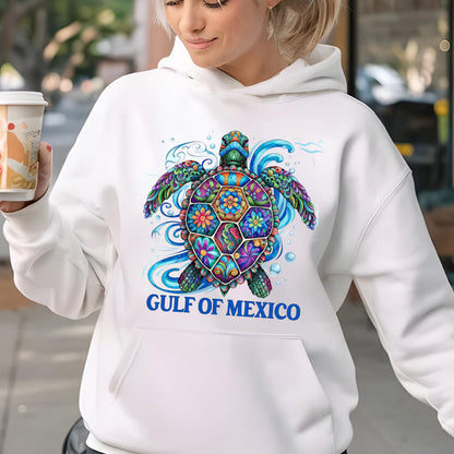 May include: White hooded sweatshirt featuring a colorful sea turtle design. The turtle has a patterned shell with floral and geometric shapes in various colors. The text "GULF OF MEXICO" is printed in blue below the turtle.