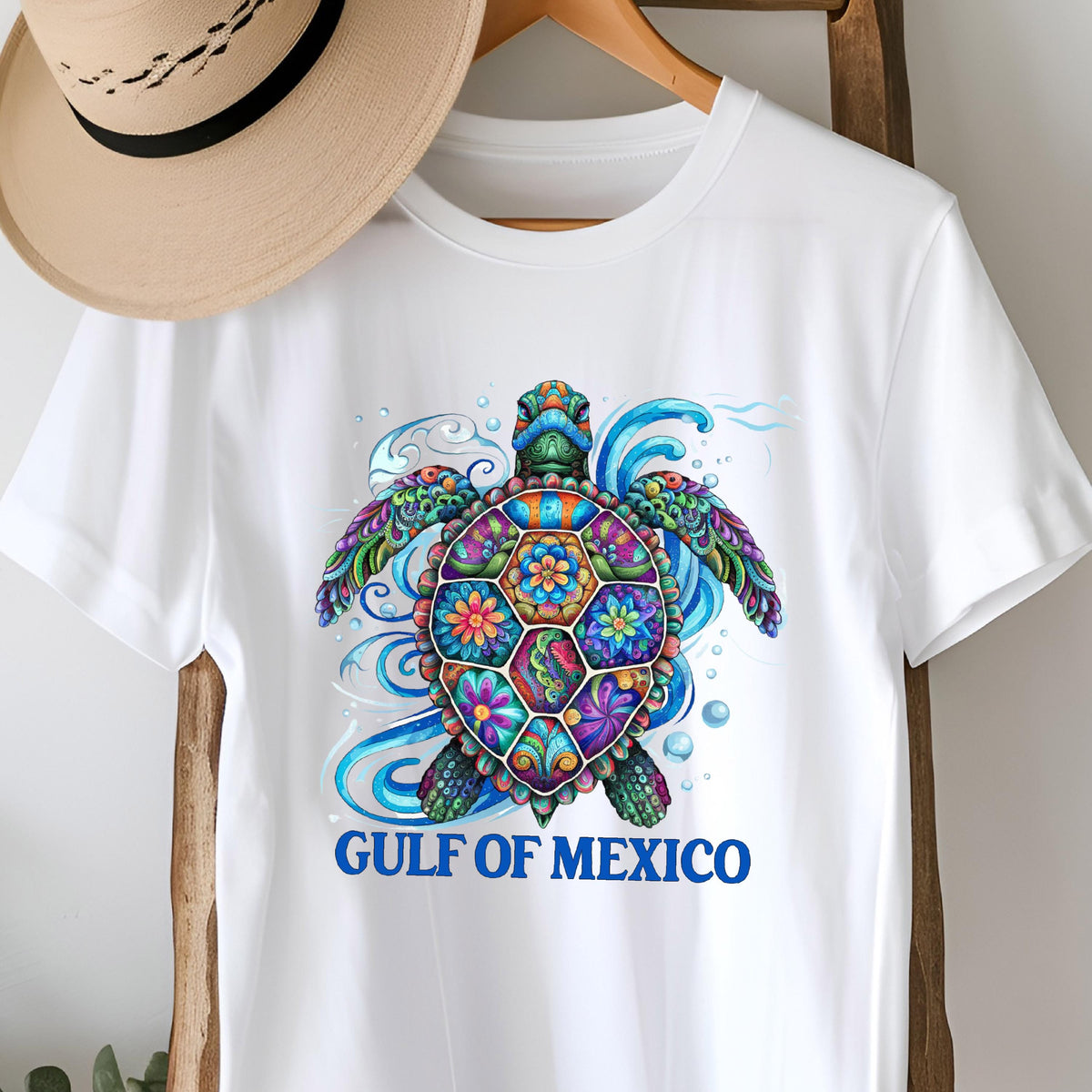 May include: White t-shirt with a colorful, detailed sea turtle design and the text "GULF OF MEXICO" in blue.