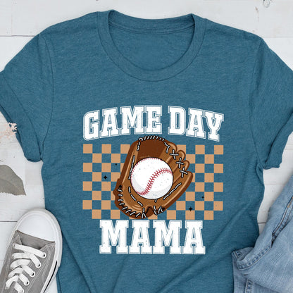 May include: A teal blue short-sleeve t-shirt featuring a graphic print with the text "GAME DAY MAMA" in white block letters. The design includes a brown baseball glove holding a white baseball, set against a tan and brown checkered background.
