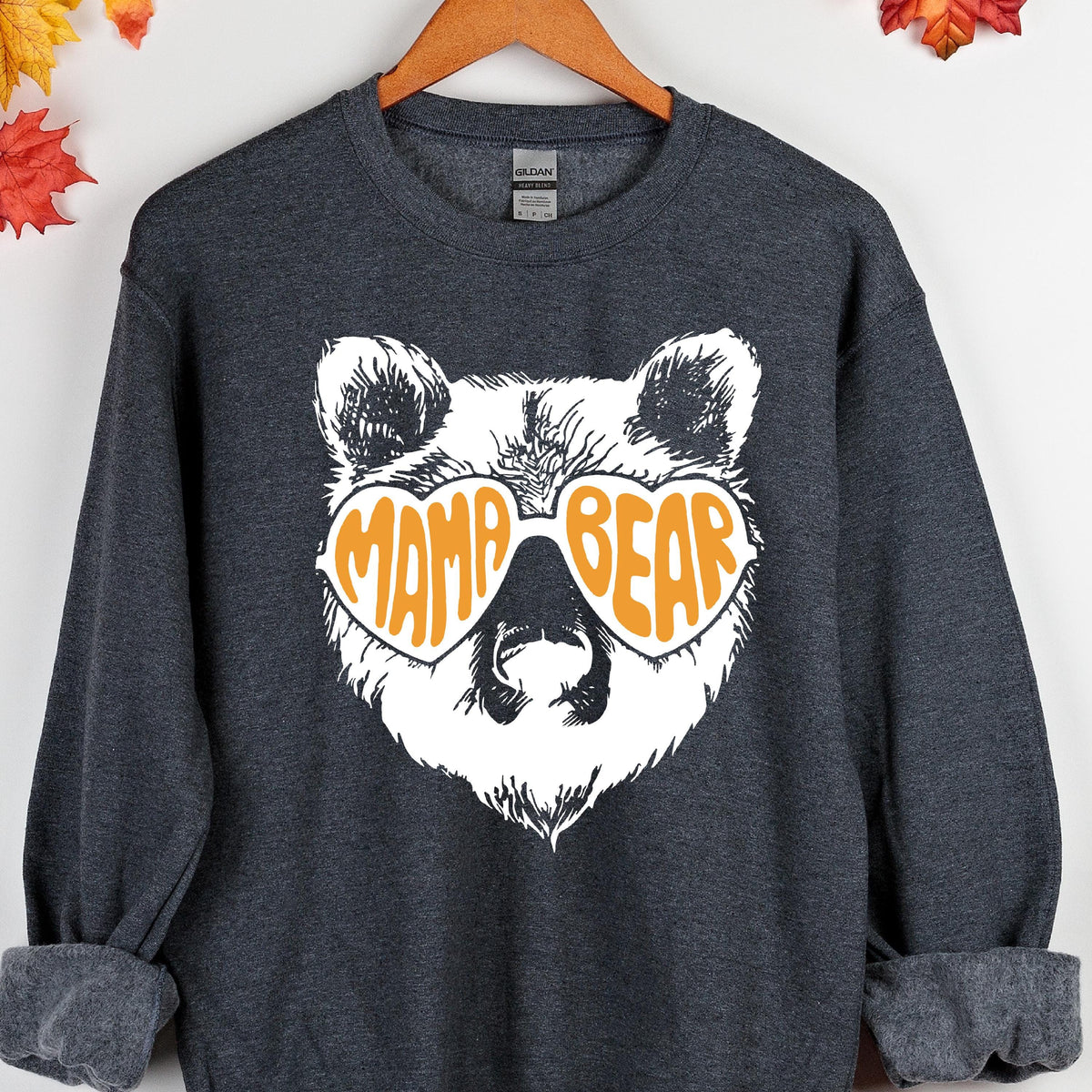 May include: A dark gray sweatshirt with a white bear wearing heart-shaped sunglasses that say "Mama Bear" in orange letters.