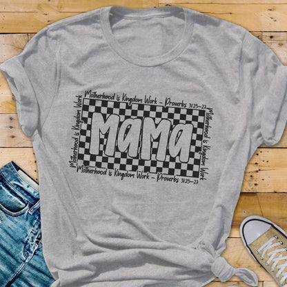 May include: Gray t-shirt with a black and white checkered design and the word "Mama" in white letters. The text "Motherhood is Kingdom Work - Proverbs 3:25-27" is written on the top and bottom of the checkered design.