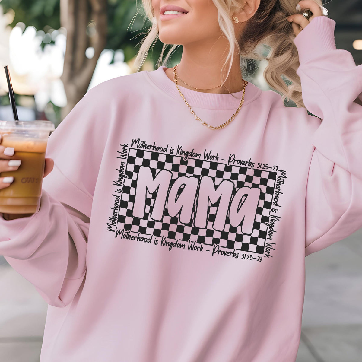 May include: Pink sweatshirt with a black and white checkered design and the word "Mama" in pink letters. The text "Motherhood is Kingdom Work - Proverbs 31:25-27" is written around the checkered design.