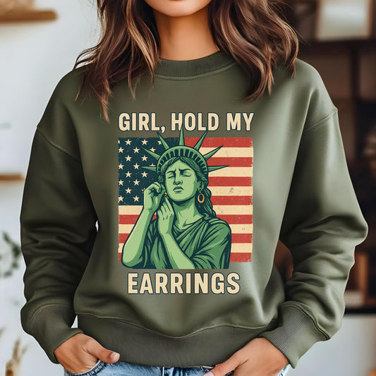 May include: Green sweatshirt with the text "Girl, Hold My Earrings" and a graphic of the Statue of Liberty holding her ear in front of an American flag.