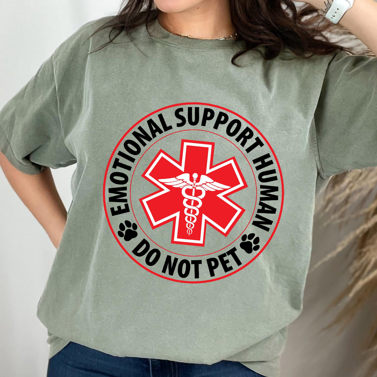 May include: A green t-shirt with a red circle and a white medical symbol. The text inside the circle reads "Emotional Support Human Do Not Pet".