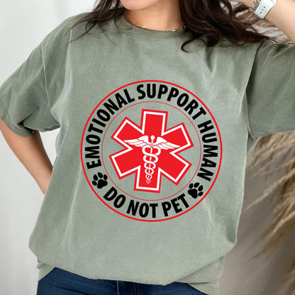 May include: A green t-shirt with a red circle and a white medical symbol. The text inside the circle reads "Emotional Support Human Do Not Pet".