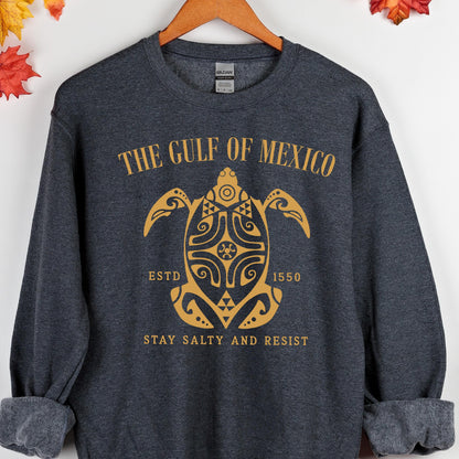 May include: A dark gray sweatshirt with a gold graphic of a sea turtle with the text "The Gulf of Mexico" above it, "Est. 1550" below it, and "Stay Salty and Resist" at the bottom.