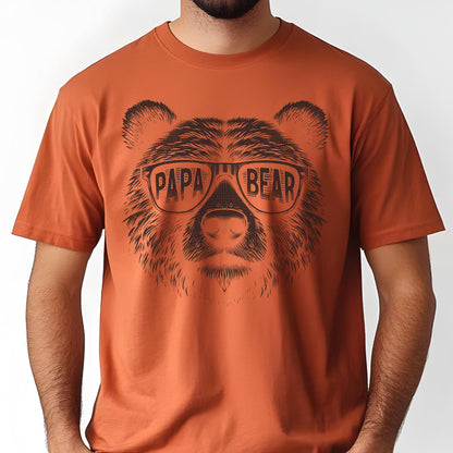 May include: Burnt orange t-shirt featuring a detailed illustration of a bear's face wearing sunglasses. The sunglasses have the words "PAPA BEAR" printed across the lenses in a bold, sans-serif font. The shirt is short-sleeved.