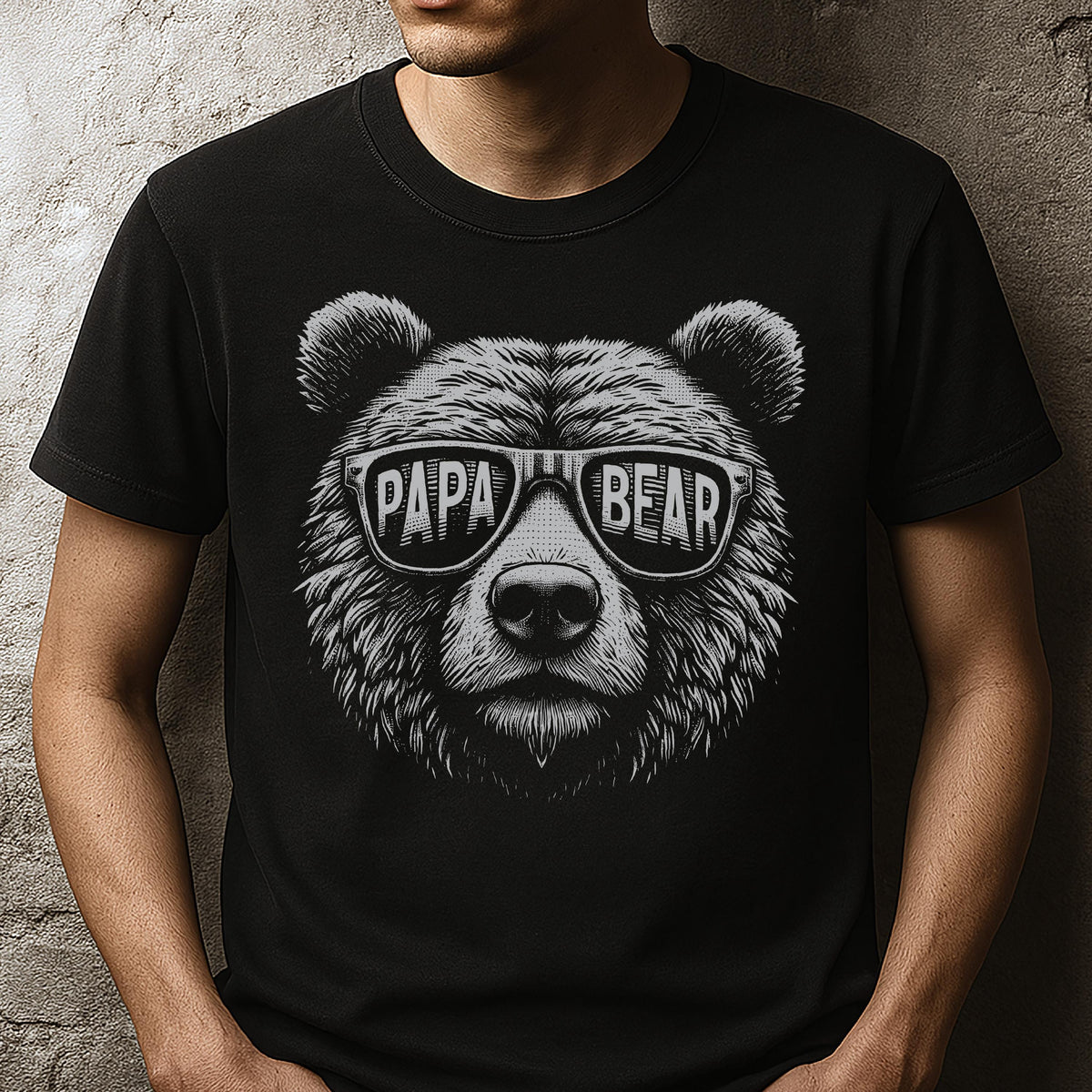 May include: Black t-shirt featuring a detailed illustration of a bear's face wearing sunglasses. The sunglasses have the words "PAPA BEAR" printed on them in a bold, white font. The bear's fur is textured, and the design is in black and white.