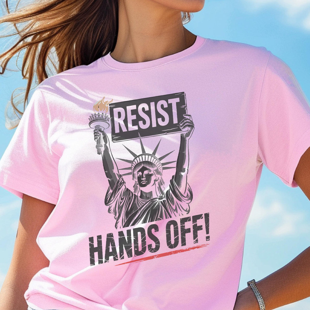 May include: Pink t-shirt with a graphic of the Statue of Liberty holding a sign that says "Resist" and the text "Hands Off!"