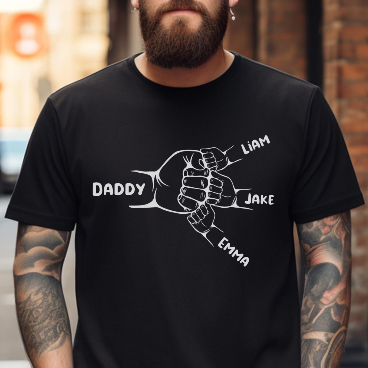 May include: Black t-shirt with a white graphic of four hands clasped together. The hands are labeled "Daddy", "Liam", "Jake", and "Emma".