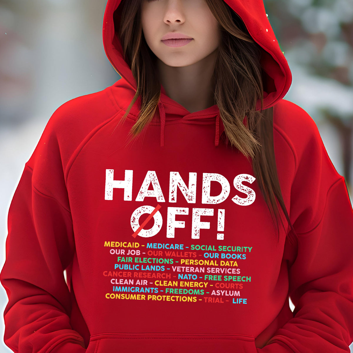 May include: Red hooded sweatshirt with the text "HANDS OFF!" in white with a red slash through the "O" in "OFF". Below the text is a list of items in rainbow colors, including "Medicaid", "Medicare", "Social Security", "Our Job", "Our Wallets", "Our Books", "Fair Elections", "Personal Data", "Public Lands", "Veteran Services", "Cancer Research", "NATO", "Free Speech", "Clean Air", "Clean Energy", "Courts", "Immigrants", "Freedoms", "Asylum", "Consumer Protections", "Trial", and "Life".