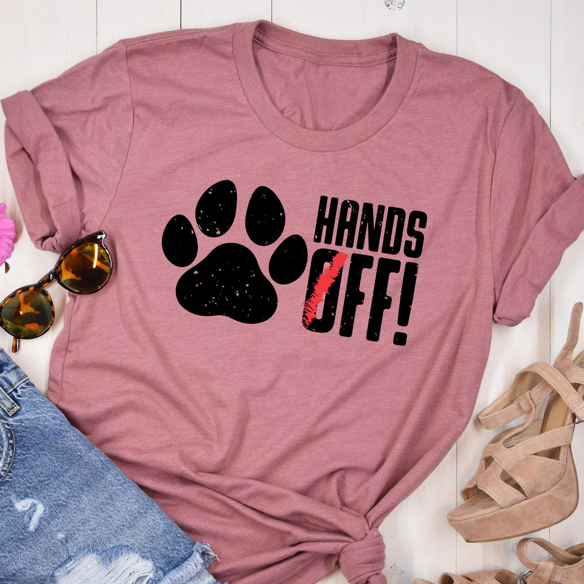 May include: A pink t-shirt with a black paw print and the text "HANDS OFF!" in black.