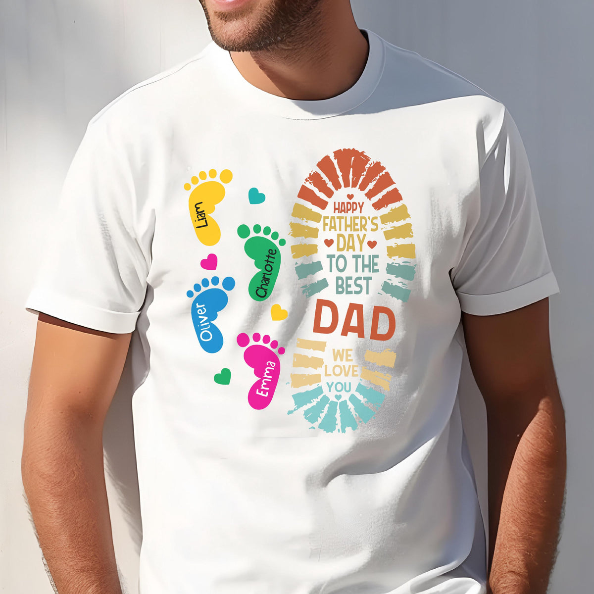 May include: White t-shirt with a colorful design for Father's Day. The design includes footprints in yellow, green, blue, and pink, with names, and a large footprint shape with the text "Happy Father's Day to the Best Dad."