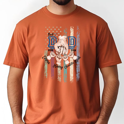 May include: Burnt orange t-shirt with a graphic design. The design features a stylized American flag with the words "Best Dad Ever" and the names "Emma, Henry, Charlotte, Noah". The design includes a fist and small hands.