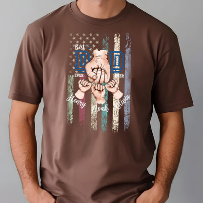May include: Brown t-shirt featuring a graphic of an American flag with the words "Best Dad Ever" and the names "Henry, Noah, Olivia". The design includes illustrations of hands and fists.