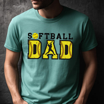 May include: A teal blue t-shirt with the text "Softball Dad" in yellow and black. The text is surrounded by a yellow softball with black stitching.