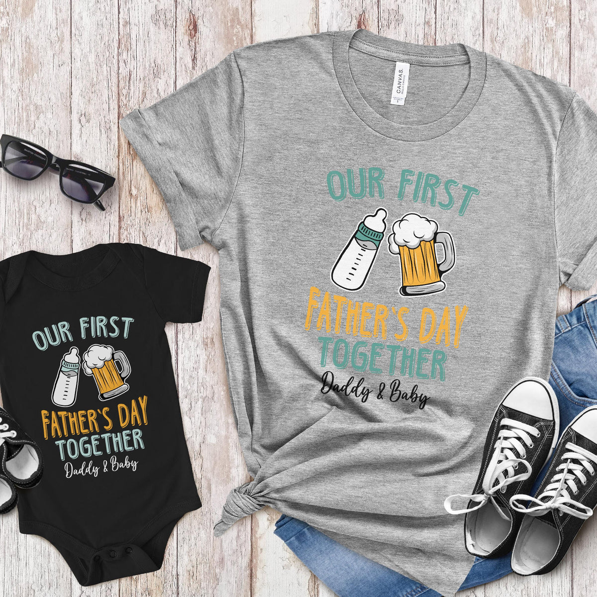 May include: A gray t-shirt and a black bodysuit with the text "Our First Father's Day Together Daddy & Baby" and a graphic of a baby bottle and a beer mug.