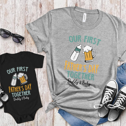 May include: A gray t-shirt and a black bodysuit with the text "Our First Father's Day Together Daddy & Baby" and a graphic of a baby bottle and a beer mug.