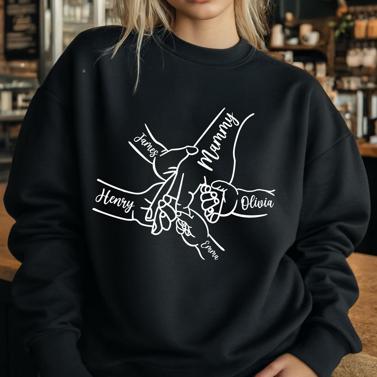 May include: Black sweatshirt with a white graphic of hands holding each other, with the names "James", "Mammy", "Henry", "Olivia", and "Emma" written on the design. The sweatshirt is made of a soft material.