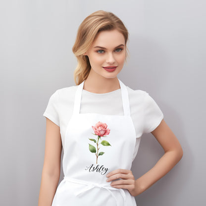 May include: White apron with a pink rose and the name "Ashley" printed on it.