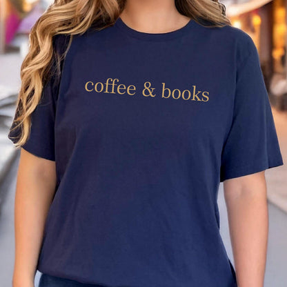 May include: A navy blue short-sleeved t-shirt featuring the text "coffee & books" printed in a gold-colored font across the chest. The garment has a classic crew neckline and a straight hemline, providing a simple and clean aesthetic.