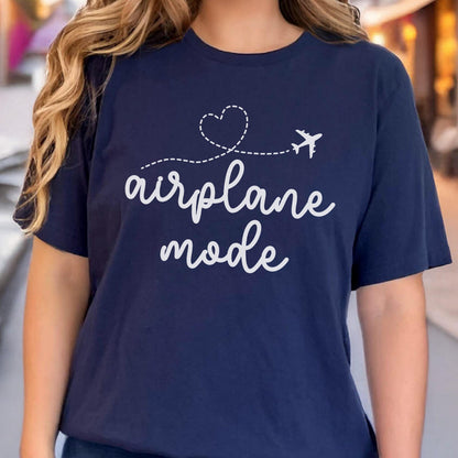 May include: Navy blue t-shirt with the words "airplane mode" in white script, accompanied by a dotted line, a heart, and a small airplane graphic. The shirt is a casual, everyday wear item.
