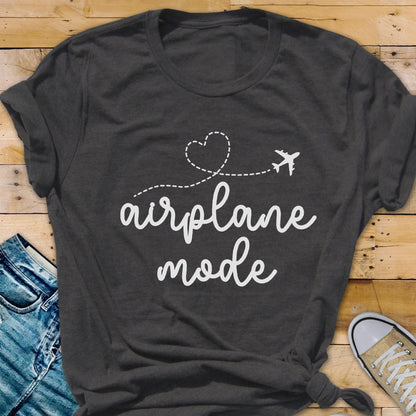May include: Dark gray t-shirt with the words "airplane mode" in a cursive font. A dotted line with a heart and airplane graphic is above the text. The shirt is folded at the sleeves.