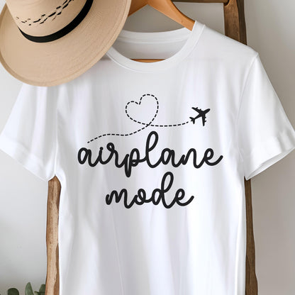 May include: White t-shirt with the words "airplane mode" in a black script font. A dotted line with a heart and airplane graphic is above the text. A tan hat hangs on a wooden hanger above the shirt.
