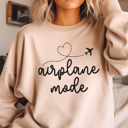May include: A beige crewneck sweatshirt featuring black text that reads airplane mode. Above the text is a black graphic of a dashed flight path forming a heart shape, ending with a small airplane silhouette flying toward the right side.