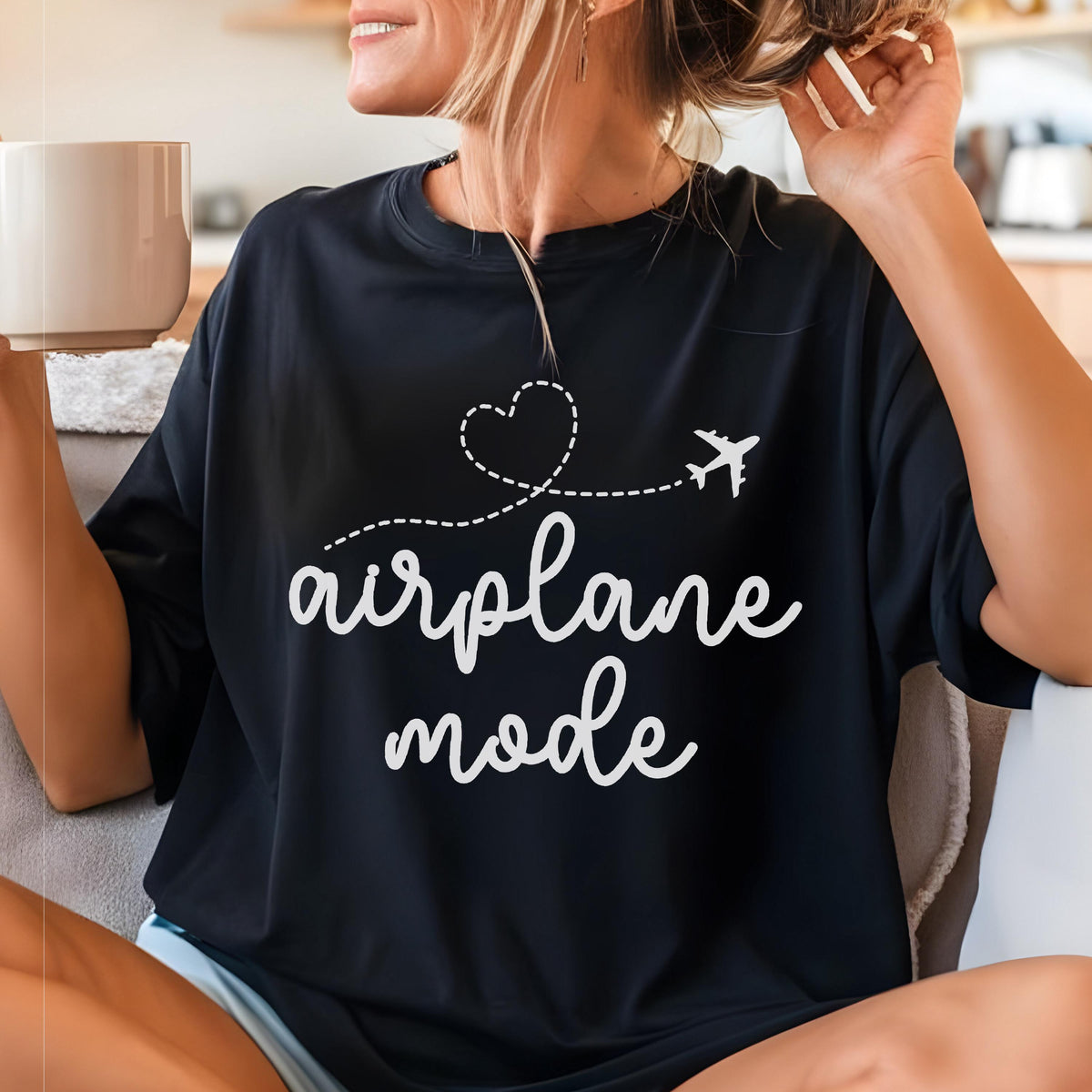 May include: Black t-shirt with the words "airplane mode" in white script. A white airplane graphic and a heart-shaped dotted line are above the text. The shirt is a casual style.