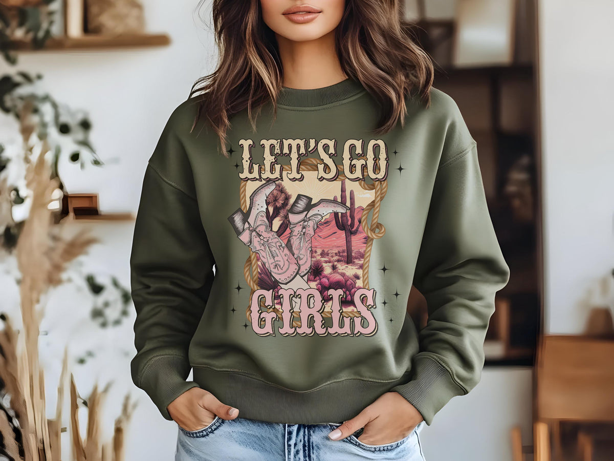 May include: A green sweatshirt with a graphic print of cowboy boots, a desert landscape, and the text "Let's Go Girls".