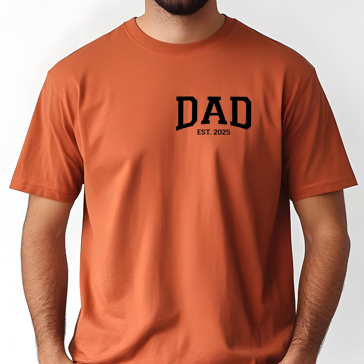 May include: A burnt orange t-shirt with the text "DAD EST. 2025" printed on the front.