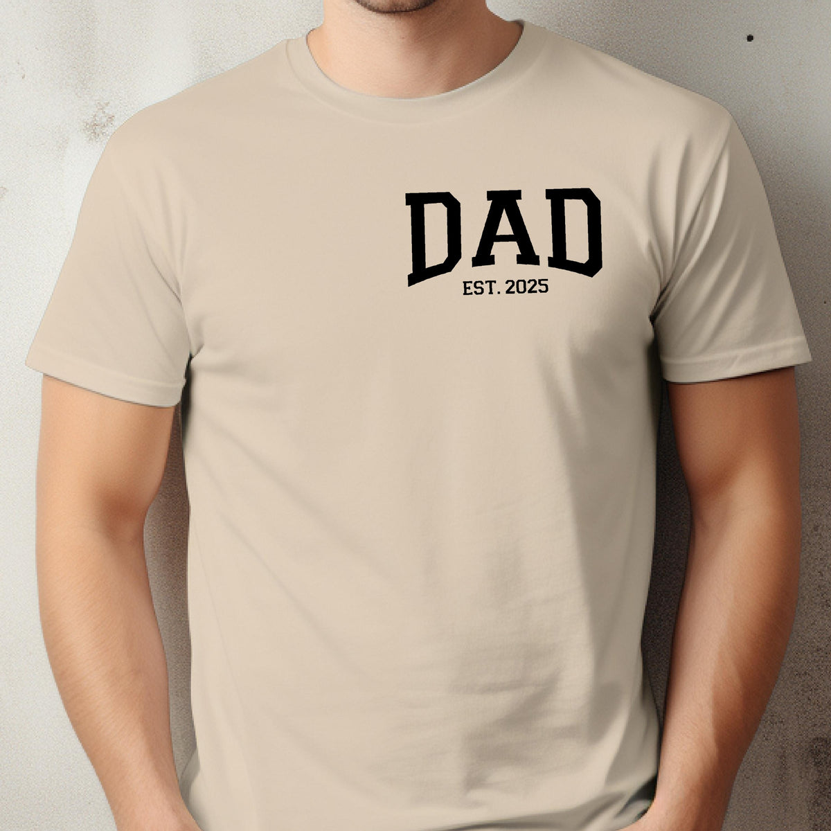 May include: A beige t-shirt with black text that reads "DAD EST. 2025".