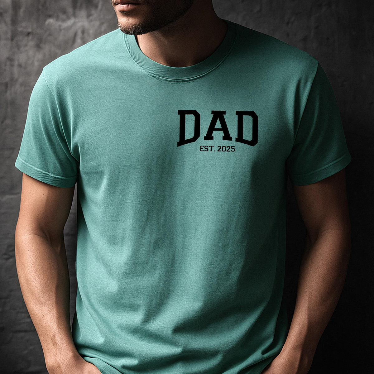 May include: A teal blue t-shirt with the word "DAD" in black block letters and the text "EST. 2025" underneath.