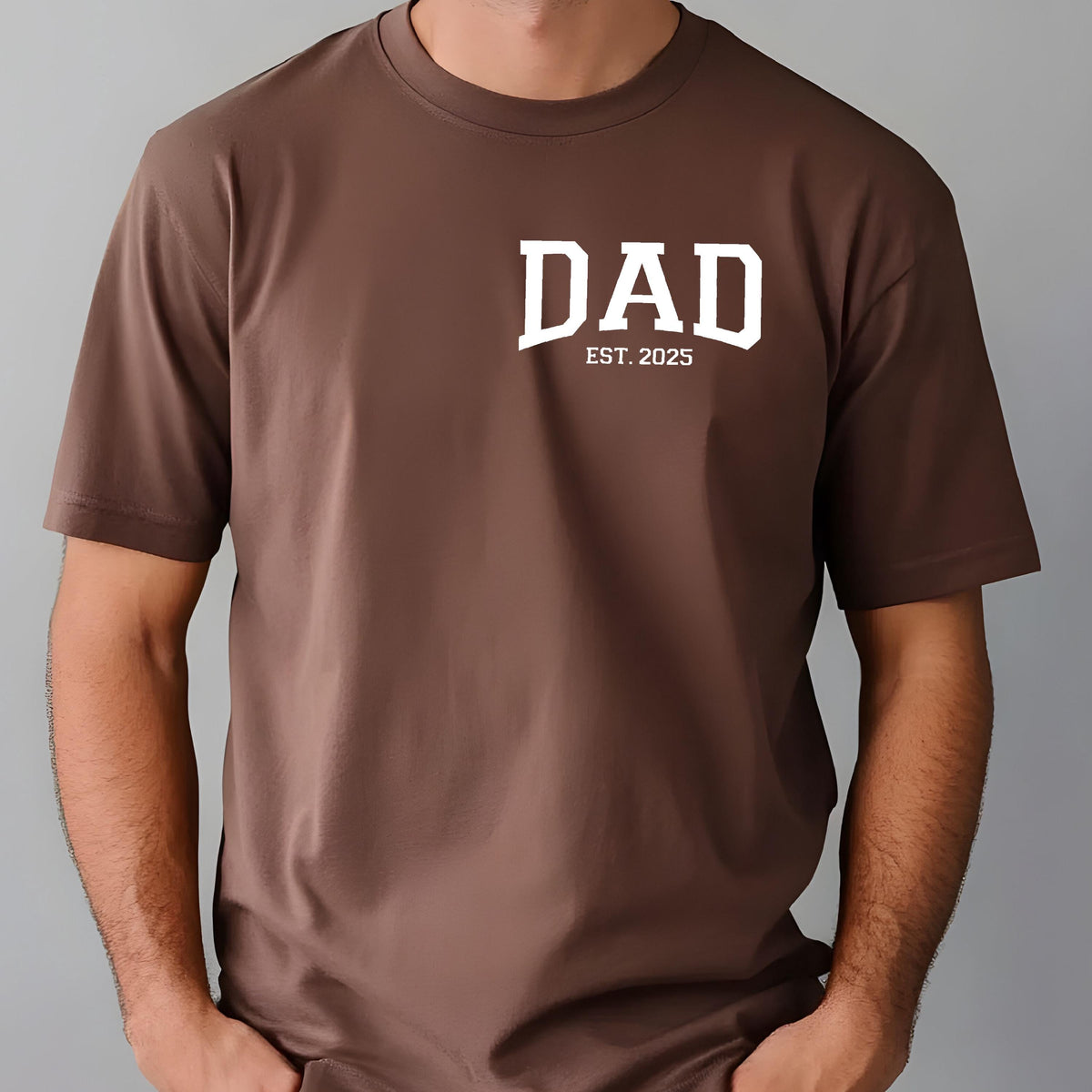 May include: A brown t-shirt with white text that reads "DAD EST. 2025".